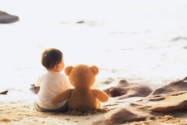 istock Baby and teddy bear sit togather on the beach 938205634