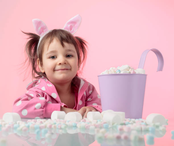 porträt eines süßen kleinen mädchens mit marshmallow auf rosa hintergrund. - child portrait fine art portrait multi colored stock-fotos und bilder