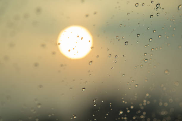 Close up of rain drops on glass with sun light.