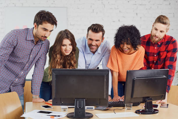 Business people, students talking at front of computer, discussing together new project
