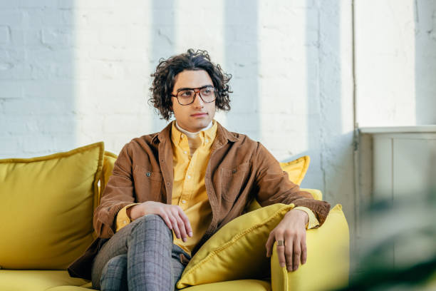 istock Young stylish man with eyeglasses sitting on couch 938226126