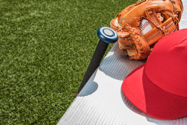 gorra de béisbol roja con un guante de béisbol y bate en banco - little league - baseball bat baseball little league baseballs fotografías e imágenes de stock