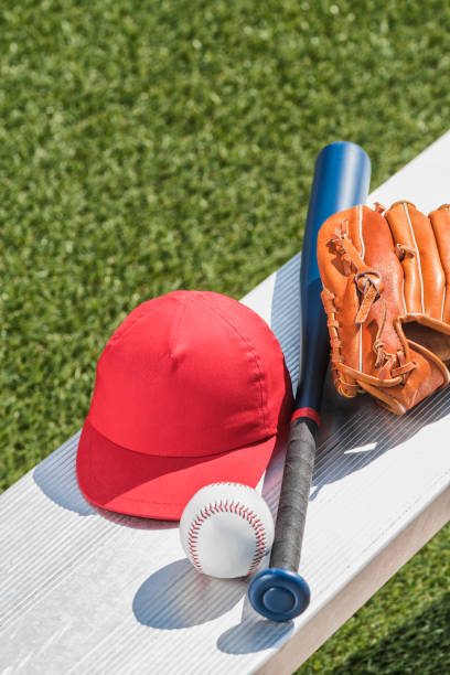 una pelota de béisbol, un gorro rojo, guante de béisbol y bate en banco - little league - baseball bat baseball little league baseballs fotografías e imágenes de stock