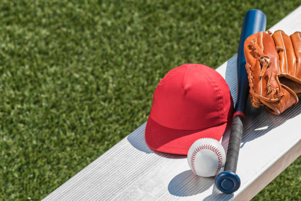 una pelota de béisbol, un gorro rojo, guante de béisbol y bate en banco - little league - baseball bat baseball little league baseballs fotografías e imágenes de stock