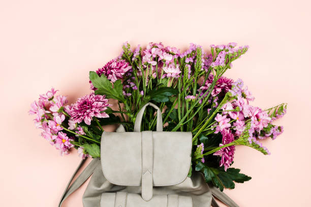 istock Grey backpack with beautiful flowers bouquet inside. Pastel background, flatlay 938255232