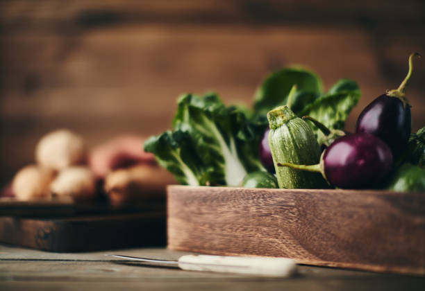Crate of assorted vegetables and chopping board shot in dark moody light