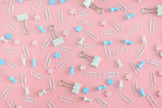 istock Cheerful pattern. Stationery chaotically scattered on a pale pink background. Staples, asterisks and buttons are in disarray. 938275668
