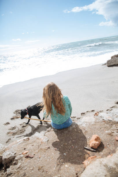 istock happy woman walking on the beach playing with her dog 938283940