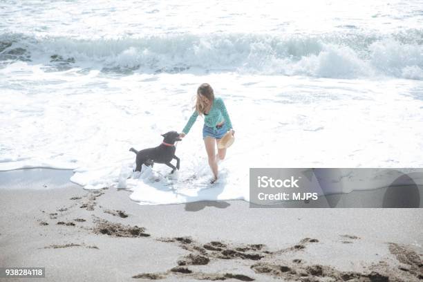Happy Woman Walking On The Beach Playing With Her Dog Stock Photo - Download Image Now