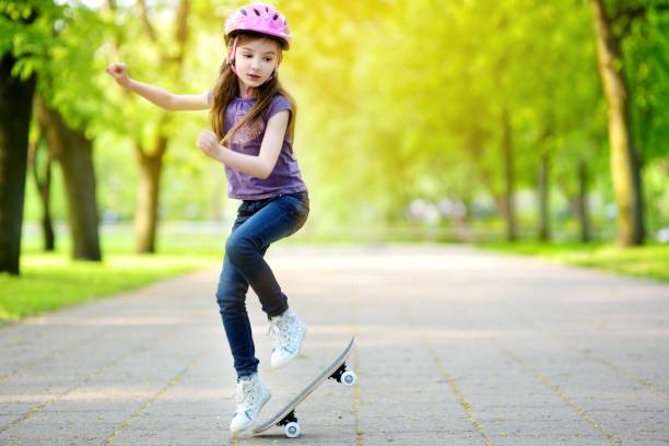 Pretty little girl learning to skateboard outdoors Pretty little girl learning to skateboard outdoors on beautiful summer day Ollie stock pictures, royalty-free photos & images