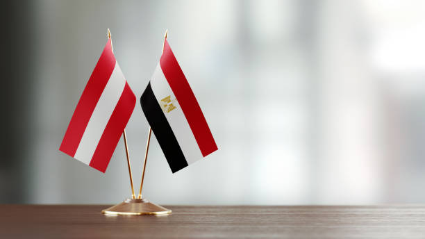 istock Austrian And Egyptian Flag Pair On A Desk Over Defocused Background 938288514