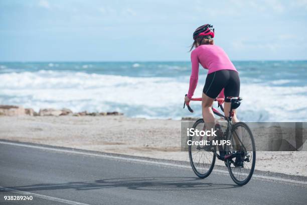 Ciclista Mujer Monta En Bicicleta En La Carretera Cerca Del Mar Foto de stock y más banco de imágenes de Andar en bicicleta