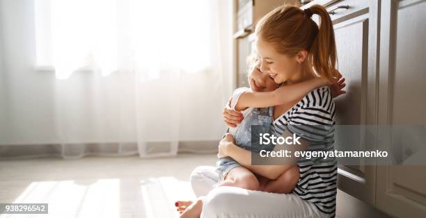 Familia Hija Madre E Hijo Abrazándose En Cocina En Piso Foto de stock y más banco de imágenes de Madre