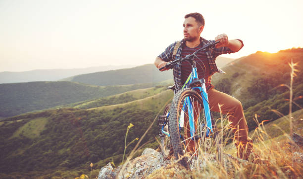 istock cycling. young man with bicycle on nature in mountains 938296934
