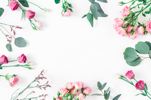 Flowers composition. Frame made of various pink flowers and eucalyptus branches on white background. Flat lay, top view, copy space