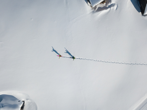 Two hikers with raised arms in deep snow from above