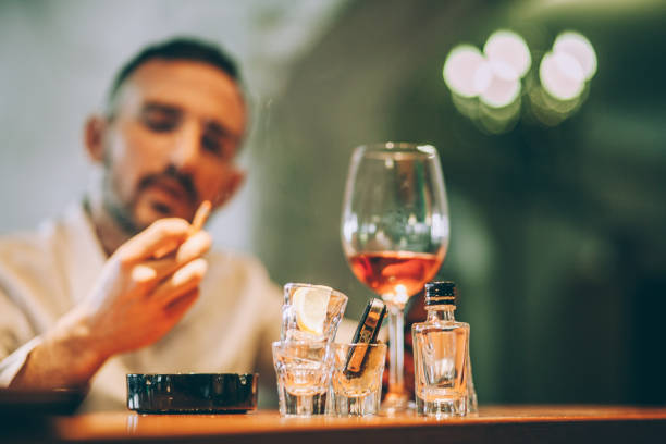 Man drinking and smoking One man, sitting at the bar counter alone, he has drinking problems. smoking or drinking alcohol stock pictures, royalty-free photos & images