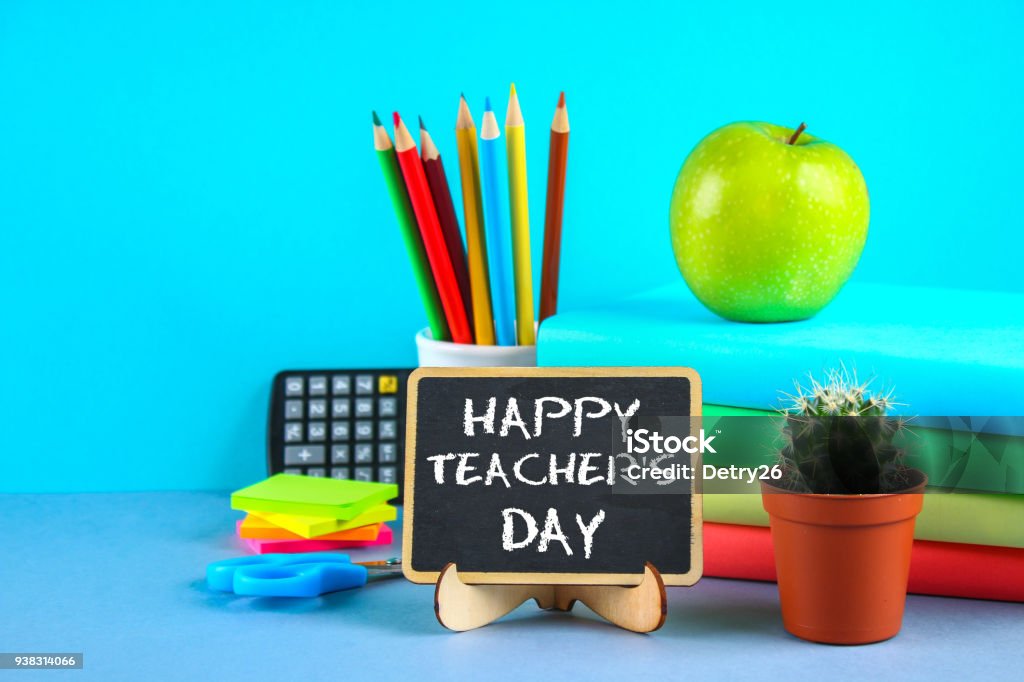 Texte de craie sur un tableau noir : journée de l’enseignant heureux. Fournitures scolaires, bureau, livres, apple. - Photo de Enseignant libre de droits