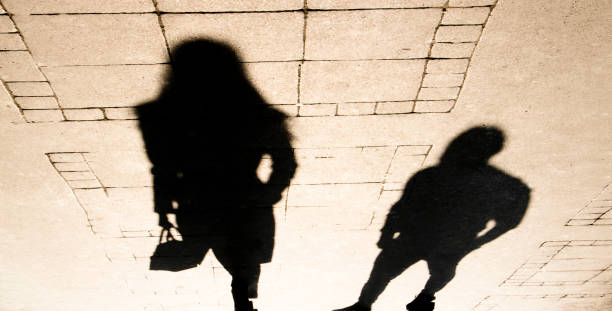 Silhouette shadow of a woman and a man on city sidewalk stock photo