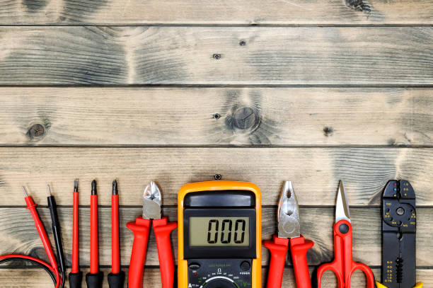 Top view of work tools for residential electrical installation on antique wooden background. Close up of work tools for residential electrical installation on an aged wooden table. Space for text / announcement. cable tester stock pictures, royalty-free photos & images