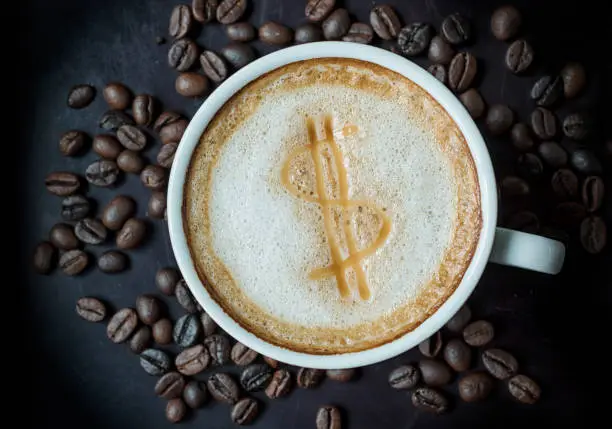 Photo of Dollar sign drawing on latte art coffee cup, top view.