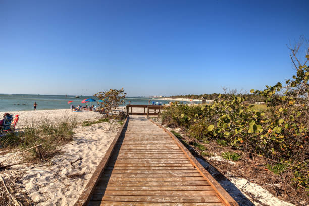 Boardwalk across the white sand beach of Delnor-Wiggins Pass State Park Boardwalk across the white sand beach of Delnor-Wiggins Pass State Park with a blue sky above in Naples, Florida. naples beach stock pictures, royalty-free photos & images