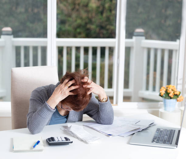 Senior woman showing depression while working on her financial matters