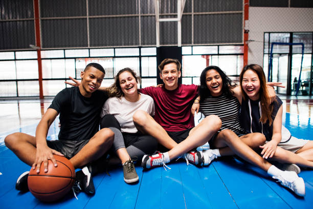 group of young teenager friends on a basketball court relaxing portrait - child basketball sport education imagens e fotografias de stock