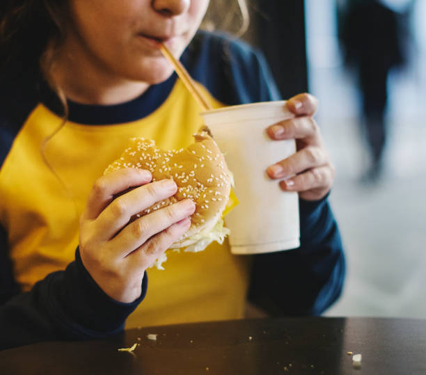 ハンバーガー肥満概念を食べる 10 代の少女のクローズ アップ - overweight child eating hamburger ストックフォトと画像