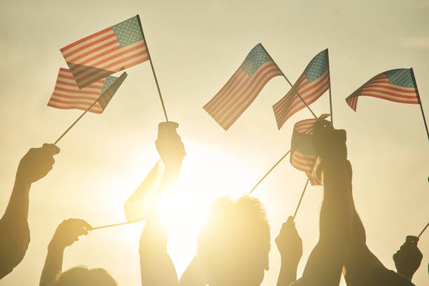 istock People hold up US flags during a rally in support. 938342732