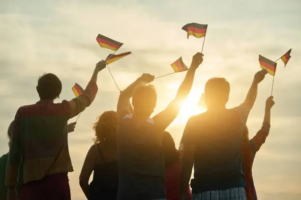 Photo of Crowd of people holding deutsch flag, back view.