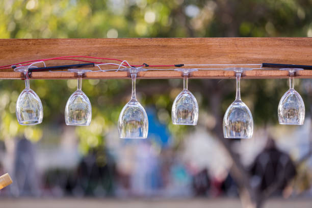 Several Wine Glasses hung on a board in a garden restaurant.