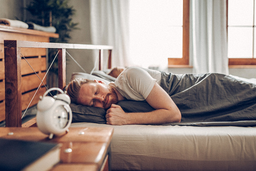 Young man in bed late for work