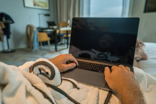 istock Young man using computer in hotel room, business travel 938368486