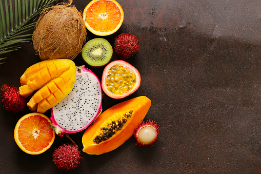 fresh tropical fruits - rambutan, papaya, kiwi, mango on a wooden background
