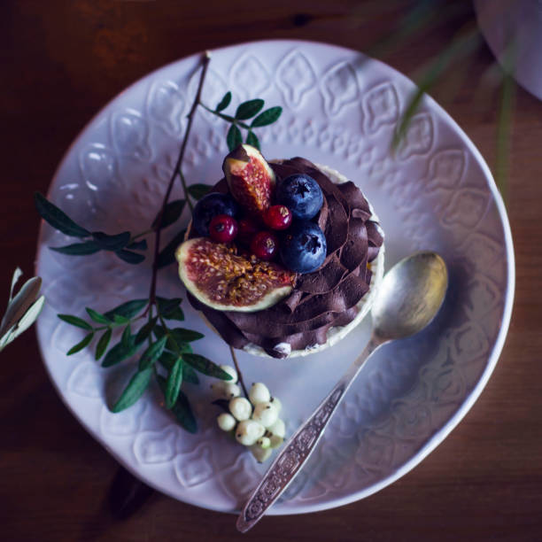 istock Chocolate cupcake with figs and berries on wooden table. View from top 938379548