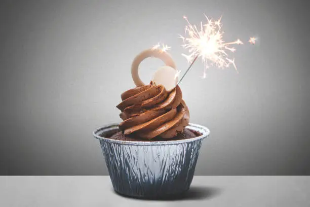 Picture of tasty chocolate cupcake with firework on the table