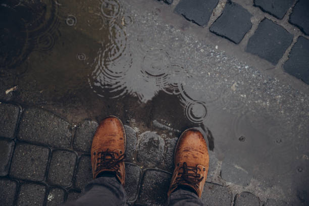 mans legs next to puddle. rainy weather.