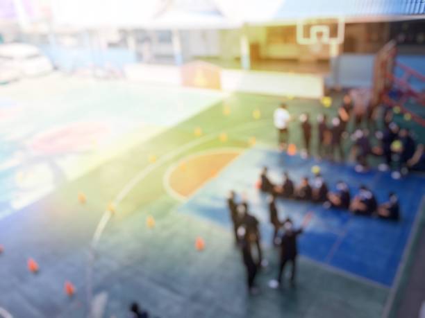 image floue des enfants ou des étudiants et étudiantes du secondaire apprennent le football ou soccer sur cour de récréation dans le temps de l’éducation physique. bangkok, thaïlande. concept d’activités physiques - secondary action photos et images de collection