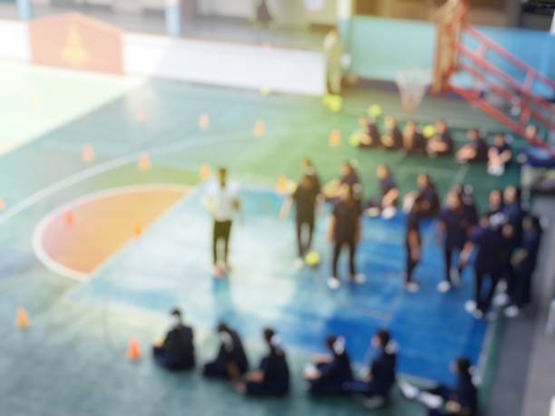 image floue des enfants ou des étudiants et étudiantes du secondaire apprennent le football ou soccer sur cour de récréation dans le temps de l’éducation physique. bangkok, thaïlande. concept d’activités physiques - secondary action photos et images de collection