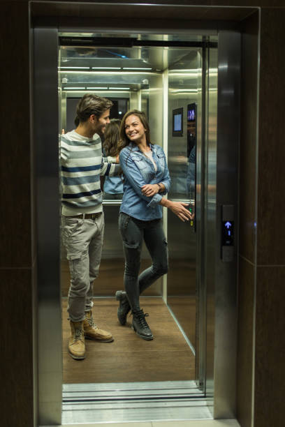 istock Young happy couple talking to each other in an elevator. 938387638