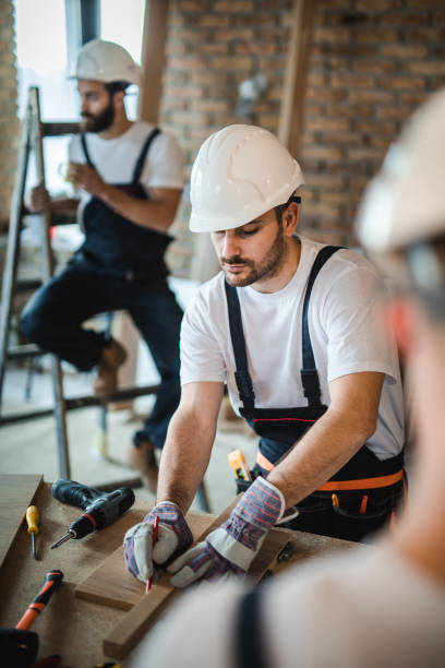 istock Young manual worker drawing measurements on a plank at construction site. 938387712