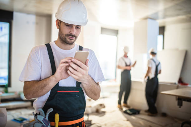 istock Male worker text messaging on smart phone while being in renovating home. 938387840