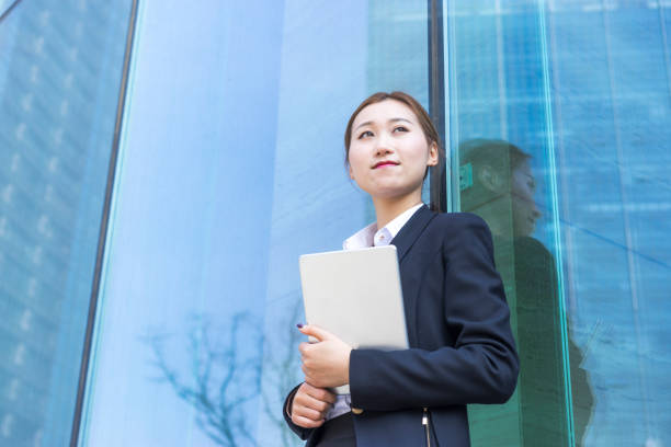 istock young business woman using tablet PC against glass wall 938389138