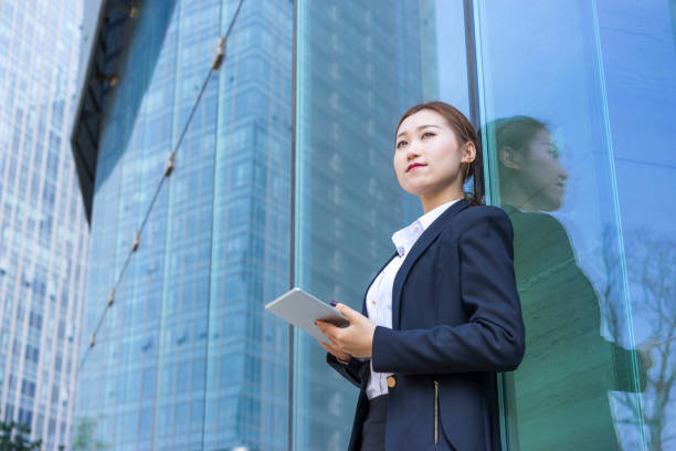 istock young business woman using tablet PC against glass wall 938389492