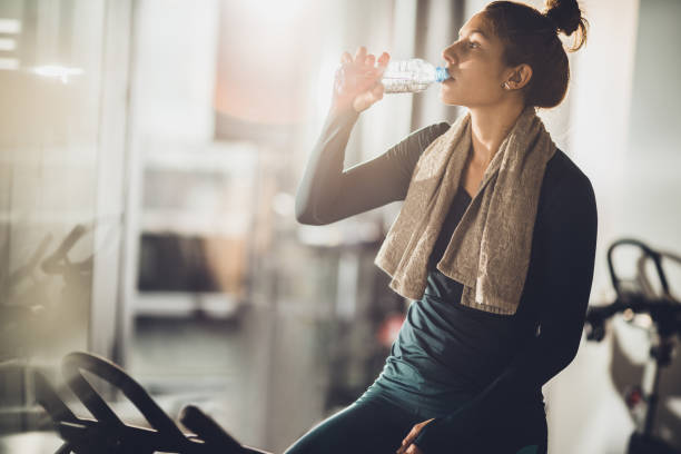 istock Thirsty athletic woman drinking fresh water on a break in a gym. 938391918