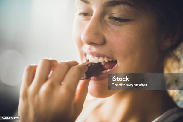 Foto de Perto De Uma Mulher Feliz Comendo Chocolate e mais fotos de stock de Chocolate - Chocolate, Comer, Mulheres