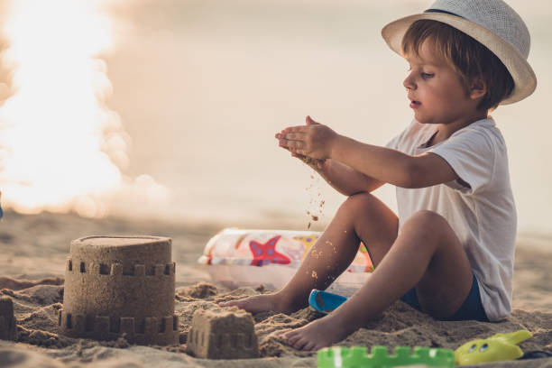 istock Cute boy playing with toys in sand on the beach. 938394964