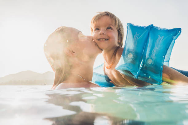 istock Affectionate mother kissing her small son in the sea. 938395438