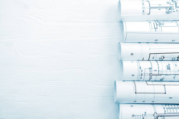 istock rolls of architectural blueprints on white wooden desk 938395500